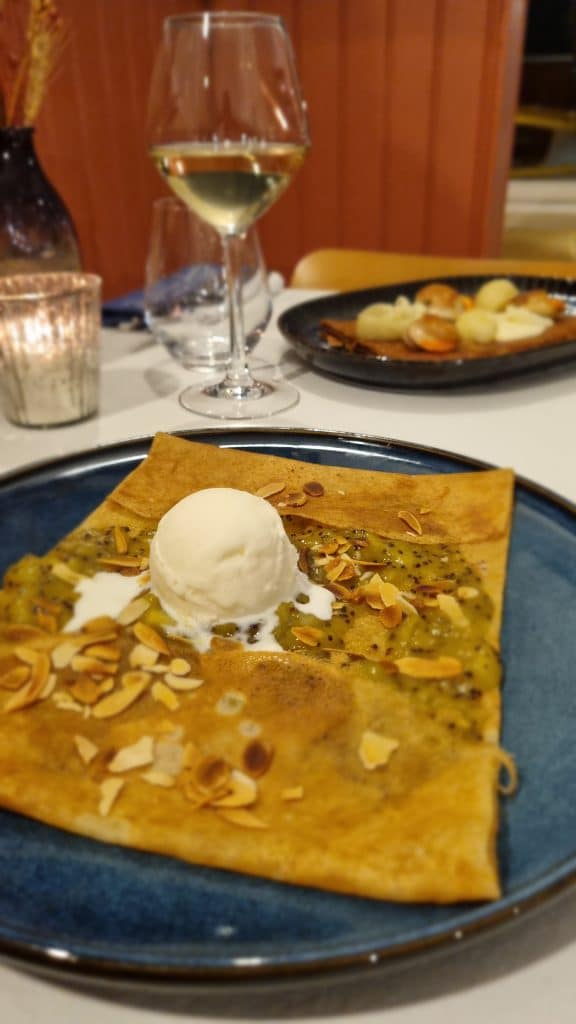 Les deux suggestions de la Crêperie Le Nazaire à Saint-Nazaire : galette Saint-Jacques et crêpe kiwi servies dans une ambiance chaleureuse avec un verre de vin blanc.