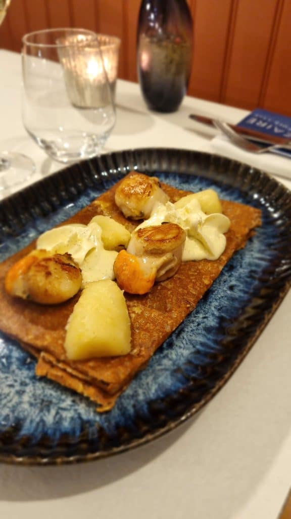 Galette Saint-Jacques servie à la Crêperie Le Nazaire à Saint-Nazaire, garnie de noix de Saint-Jacques dorées, cerfeuil tubéreux et crème montée à la vanille.