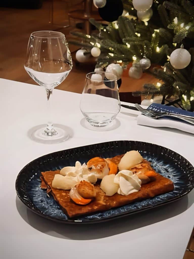 Suggestion de galette Saint-Jacques et crêpe kiwi de la Crêperie Le Nazaire à Saint-Nazaire, dressée dans une assiette élégante devant un décor chaleureux.