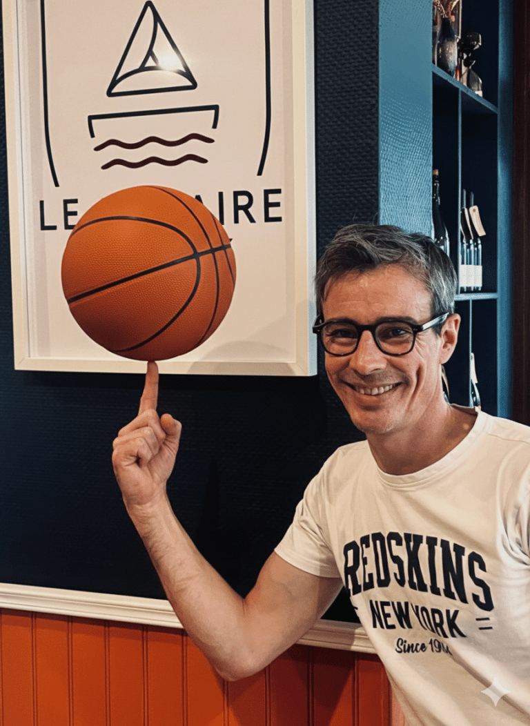 Guillaume, gérant de la Crêperie Le Nazaire à Saint-Nazaire, fait tourner un ballon de basket sur son doigt devant le logo du restaurant, pour célébrer le partenariat avec le club des Fréchets.