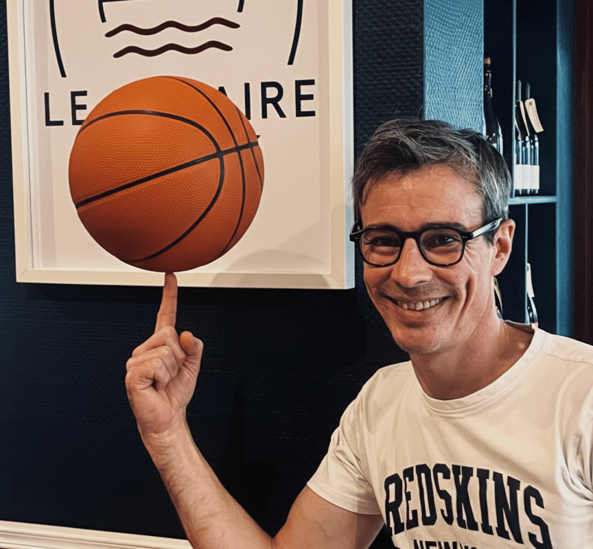 Guillaume, gérant de la Crêperie Le Nazaire à Saint-Nazaire, fait tourner un ballon de basket sur son doigt devant le logo du restaurant, pour célébrer le partenariat avec le club des Fréchets.